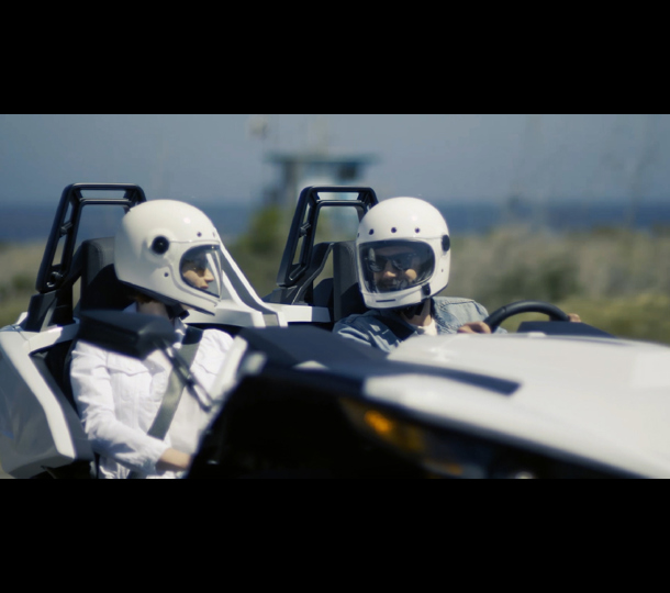 two men talking while driving a sports car
