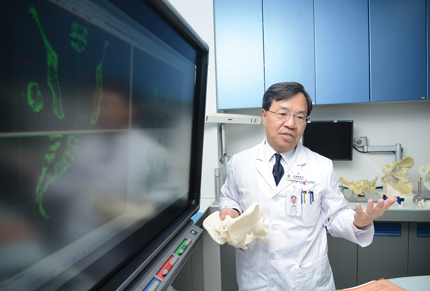 Doctor holding 3d printed bones near computer screen